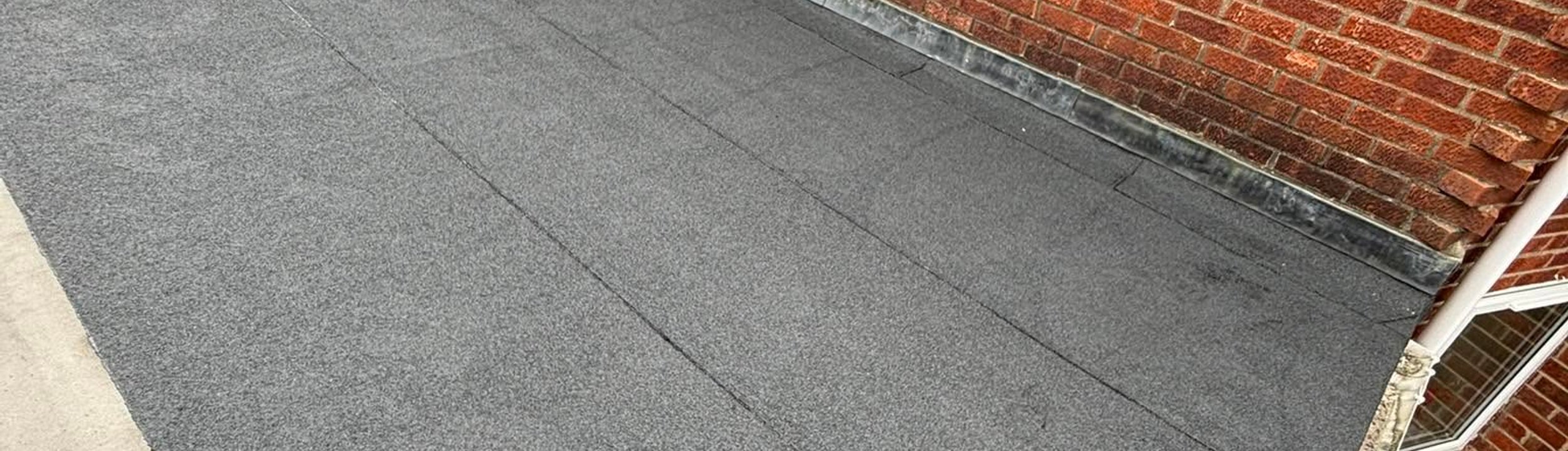 Finished flat roof edge against a brick house
