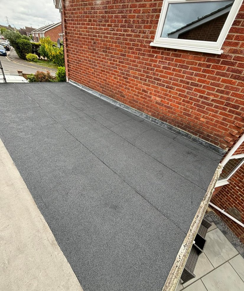 Finished felt flat roof against a brick house