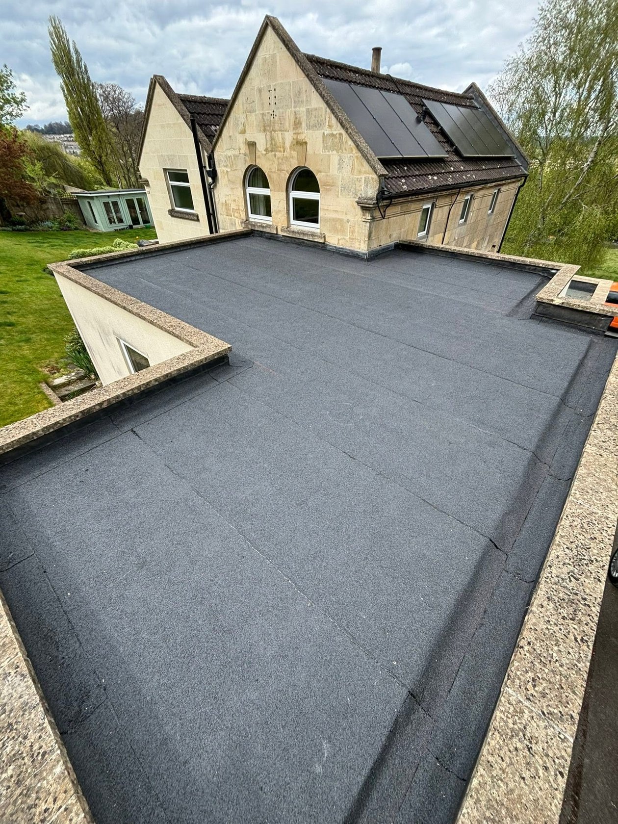 Completed flat roof beside a stone home