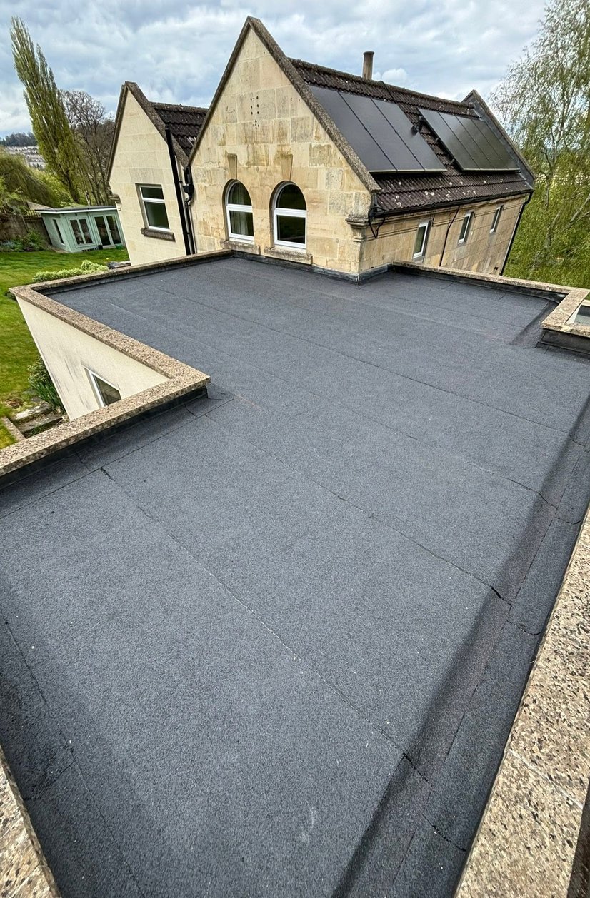 Felt flat roof beside a stone house with solar panels