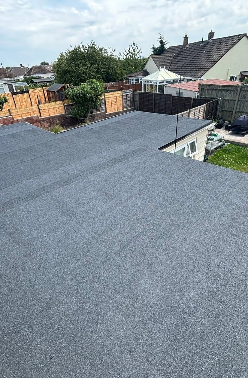 Large finished felt flat roof above residential gardens