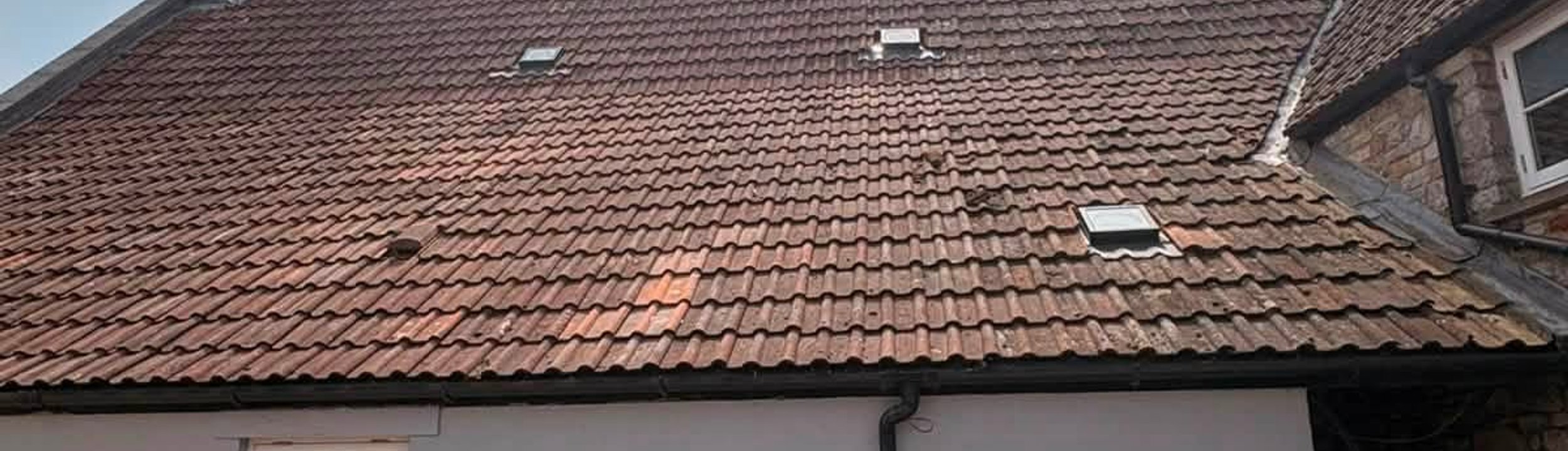 Tiled roof with two brick chimneys and roof windows